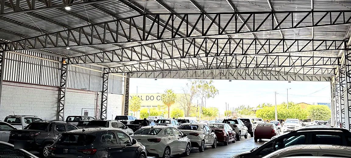 Salão de exposição da Abreu Autos com estrutura metálica e fileiras de carros até a entrada
